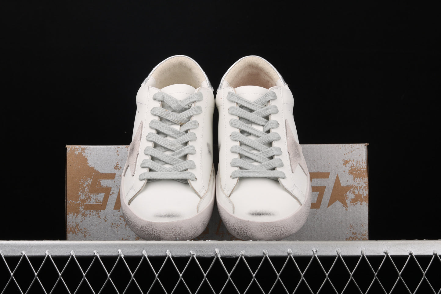 White sneakers on a metallic surface with a black background
