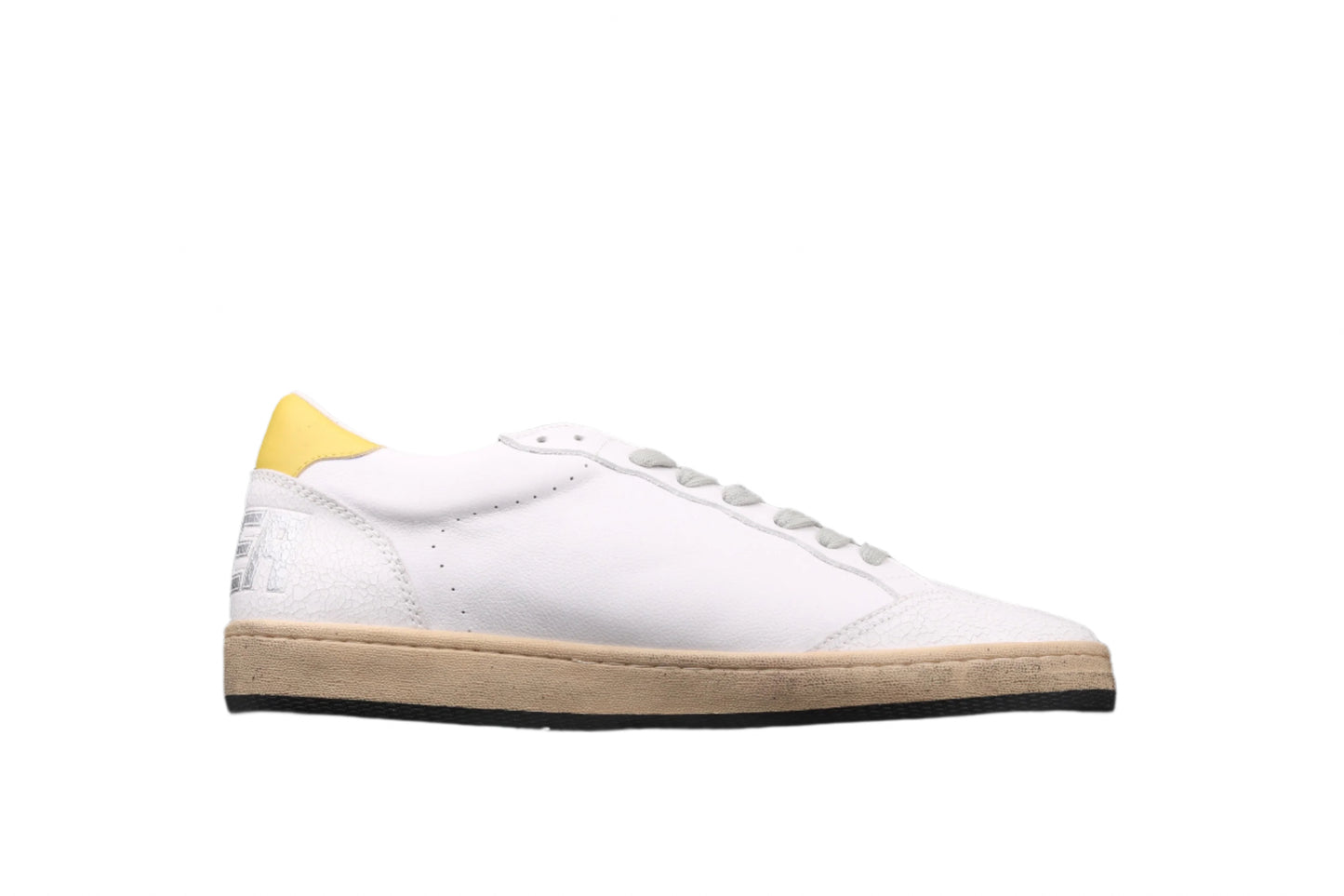 White sneaker with yellow heel on a black background