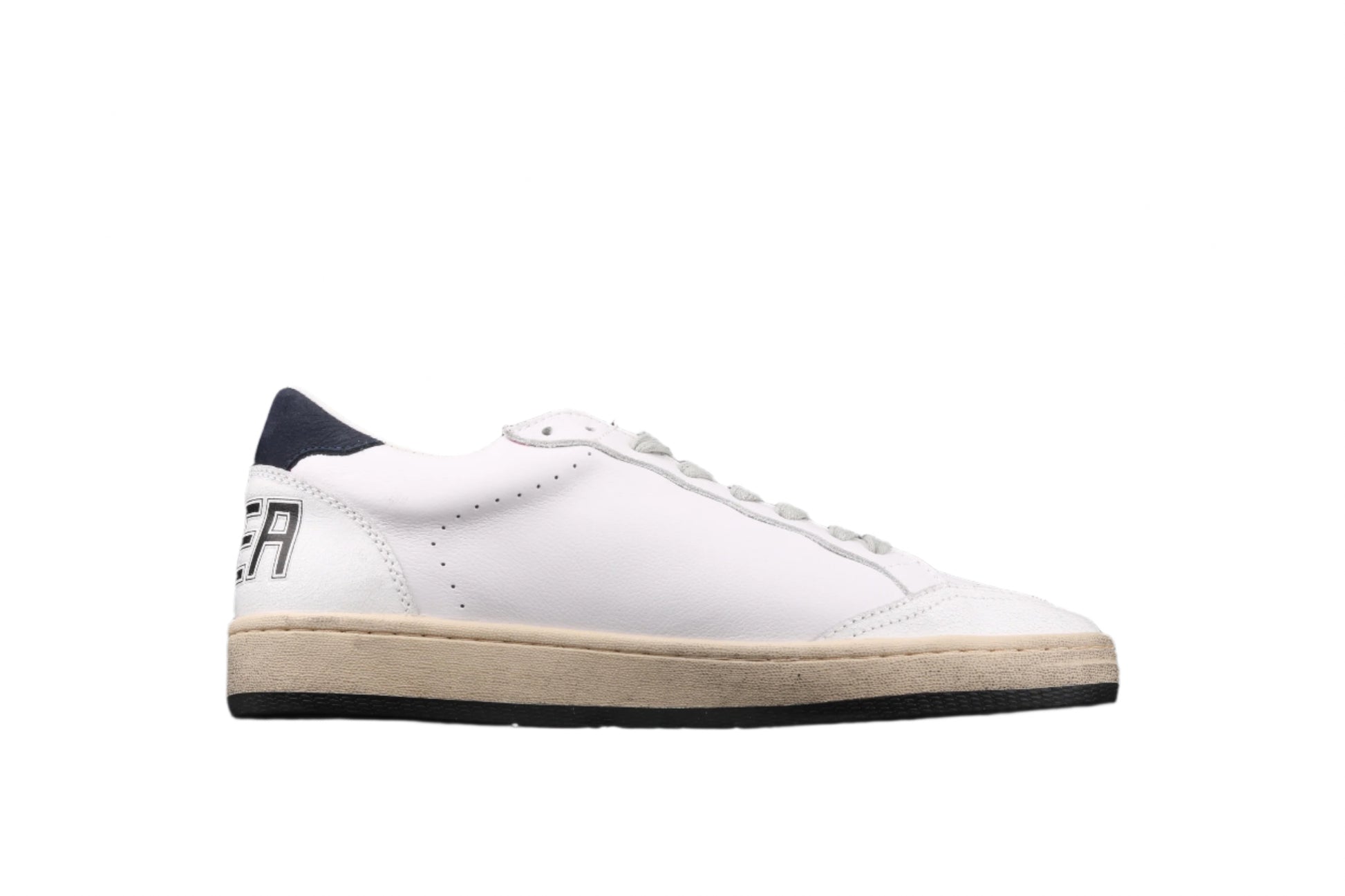 White sneaker with a black sole on a black background