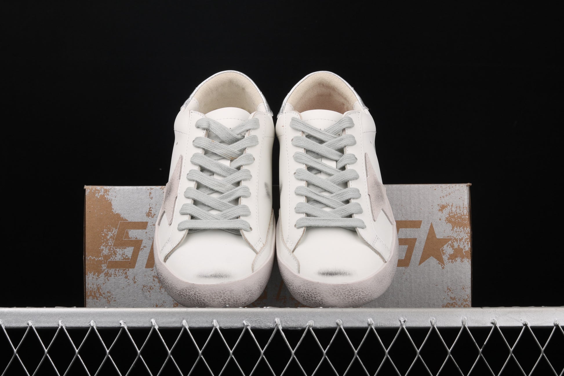 White sneakers on a metallic surface with a black background