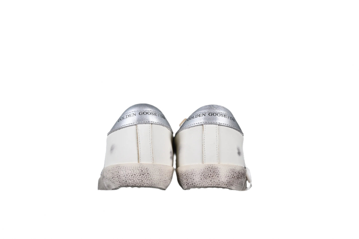 Pair of white sneakers with speckled soles on a black background