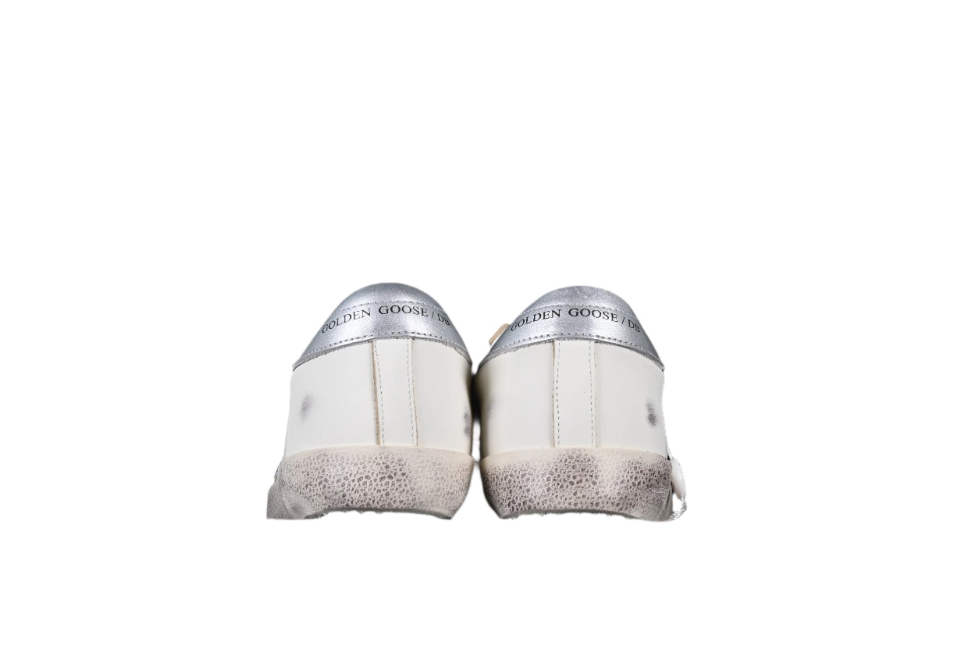Pair of white sneakers with speckled soles on a black background